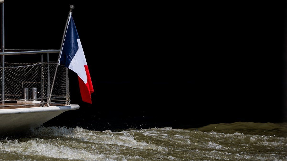 A boat with a French flag sails by on the Seine river in Paris, where concerns about the water quality have forced the cancellation of triathlon swim training session for the Paris 2024 Olympic Games, on Monday 29 July 2024 in Paris, France. 