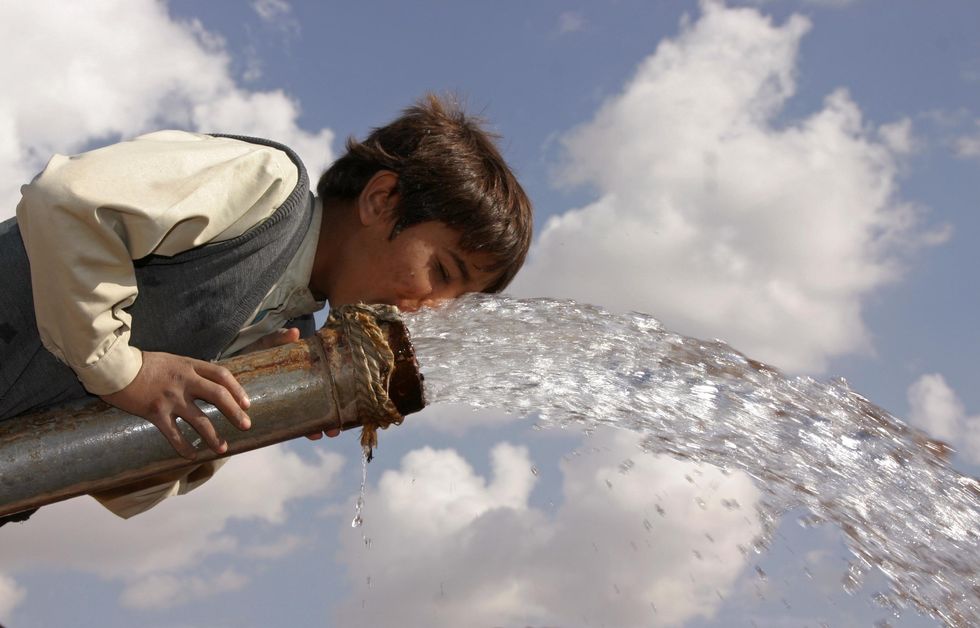 A boy drinks from a water pump in a village outside Sanaa, Yemen.