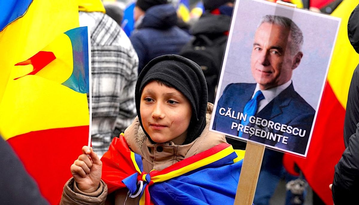 A boy holds a sign reading "Calin Georgescu President" during an anti-government rally in Bucharest, Romania. 