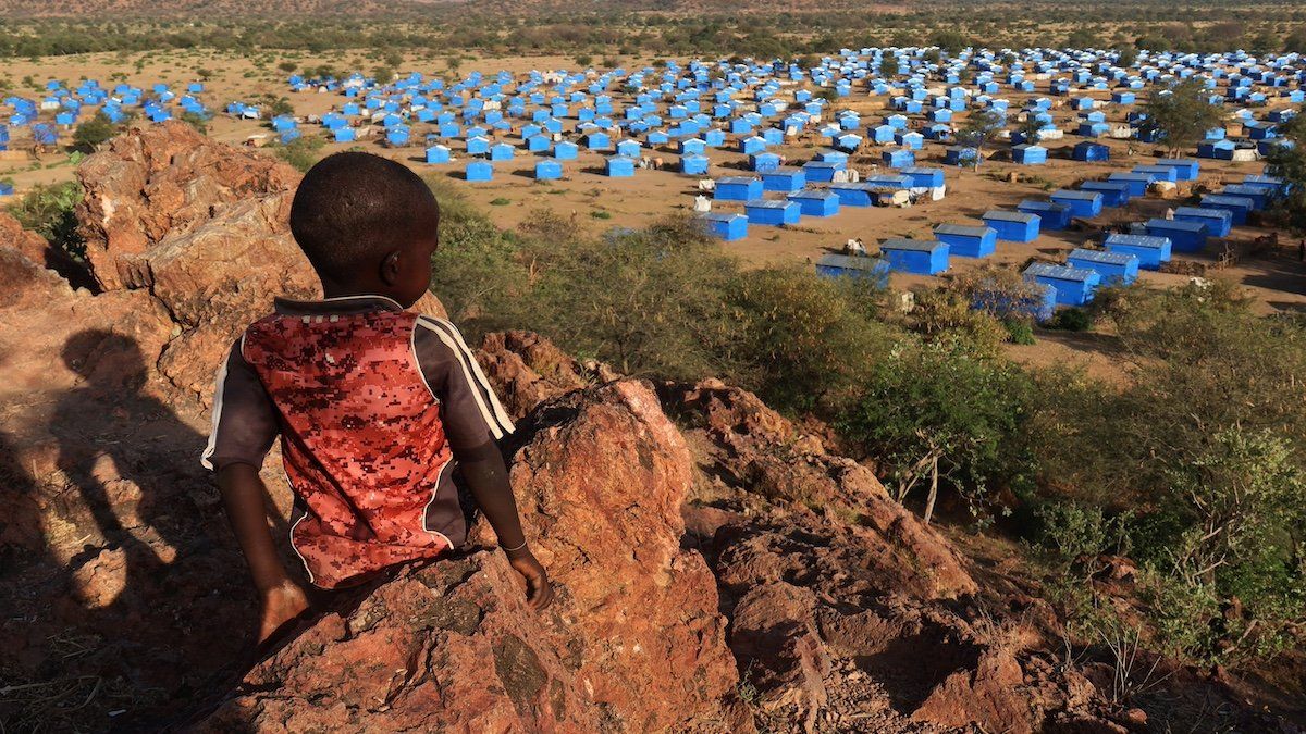 ​A boy sits atop a hill overlooking a refugee camp near the Chad-Sudan border, November 9, 2023. Hundreds of Masalit families from Sudan's West Darfur state were relocated here months after fleeing to the Chadian border town of Adre, following an ethnically targeted massacre in the city of El Geneina. 