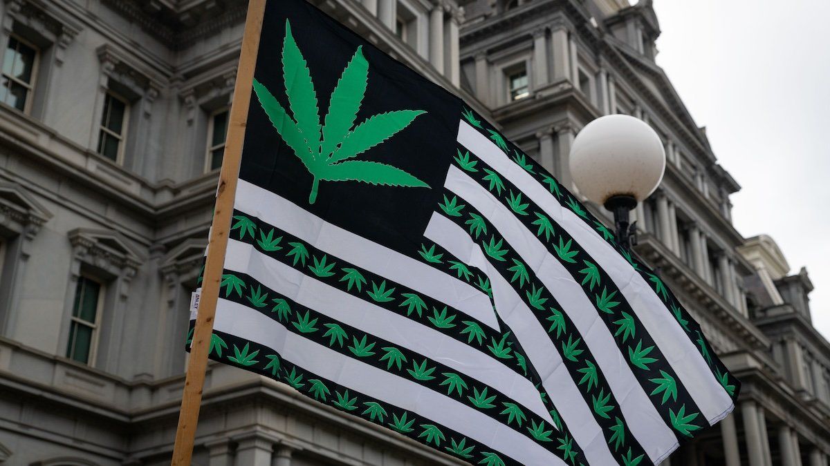A cannabis rights activist waves a flag outside the Eisenhower Executive Office Building in Washington, D.C. on Oct. 24, 2022.
