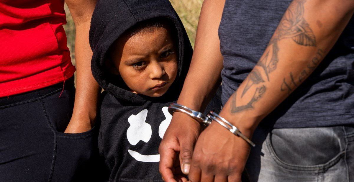 ​A child looks on as his father who illegally crossed into the U.S. from Mexico is arrested by U.S. Border Patrol agents.