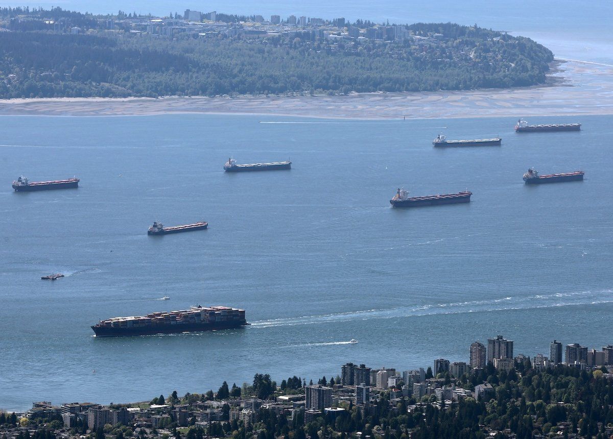 A container ship makes its way into the Port of Vancouver past vessels at anchor in English Bay, as seen from Grouse Mountain in North Vancouver, British Columbia, on May 10, 2024.