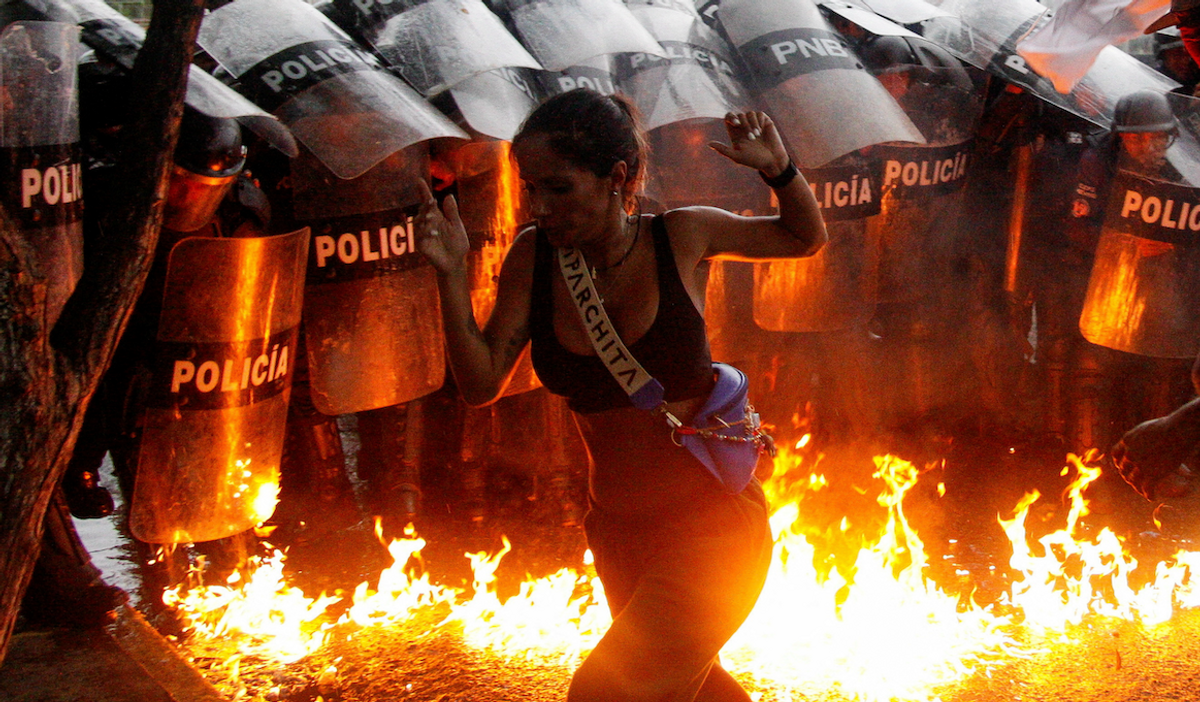 A demonstrator reacts when Molotov cocktails hit the ground in front of security forces during protests against election results after Venezuela's President Nicolas Maduro claimed victory in Sunday's presidential election, in Puerto La Cruz, Venezuela. ​