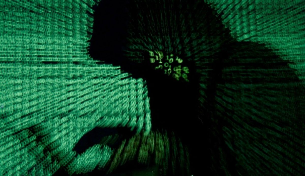 A man holds a laptop computer as cyber code is projected on him in this illustration of a hacker. 