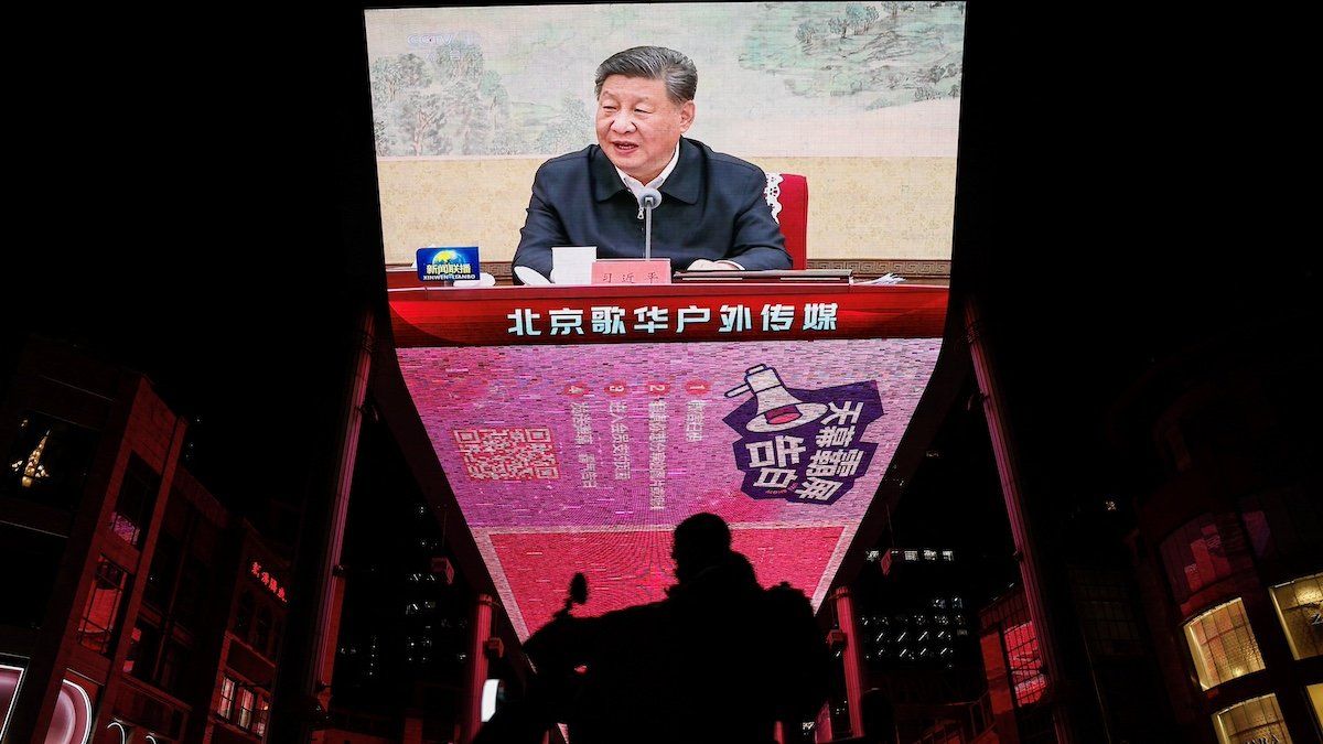 ​A man rides a scooter past a giant screen showing news footage of Chinese President Xi Jinping attending a Chinese Communist Party politburo meeting, in Beijing, China December 9, 2024. 