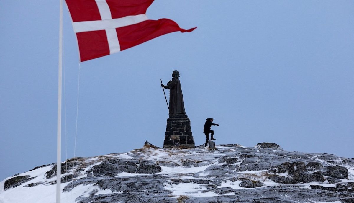 A man walks as a Danish flag flutters next to Hans Egede Statue ahead of a March 11 general election in Nuuk, Greenland, March 9, 2025. 