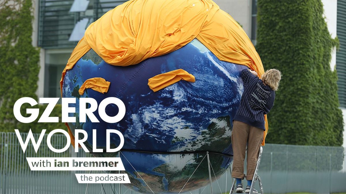 A person wrapping a yellow, curtain-like material over a large globe to form a likeness of US President-elect Donald Trump’s face, with text art reading 'GZERO World with Ian Bremmer – the podcast.'