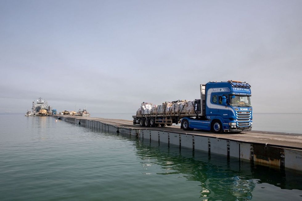 ​A truck carries humanitarian aid across a temporary pier to deliver aid off the Gaza Strip. 