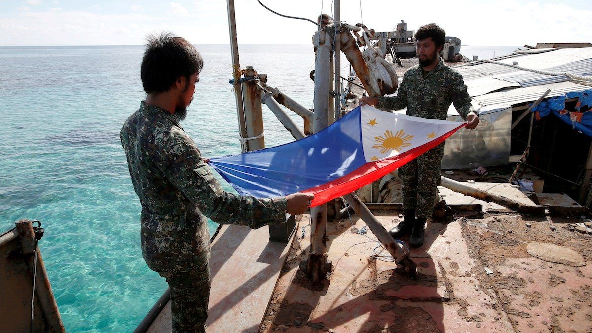 FILE PHOTO: Philippine Marines fold a Philippine national flag during a flag retreat at the BRP Sierra Madre, a marooned transport ship in the disputed Second Thomas Shoal, part of the Spratly Islands in the South China Sea, March 29, 2014. 