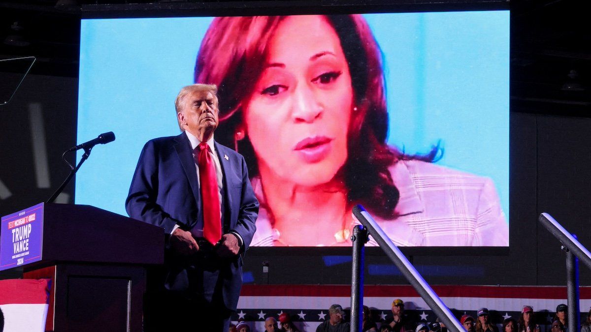 FILE PHOTO: Republican presidential nominee and former U.S. President Donald Trump looks on as Democratic presidential nominee and U.S. Vice President Kamala Harris' face appears as a video plays on a screen, during a rally at Huntington Place in Detroit, Michigan, U.S. October 18, 2024. 