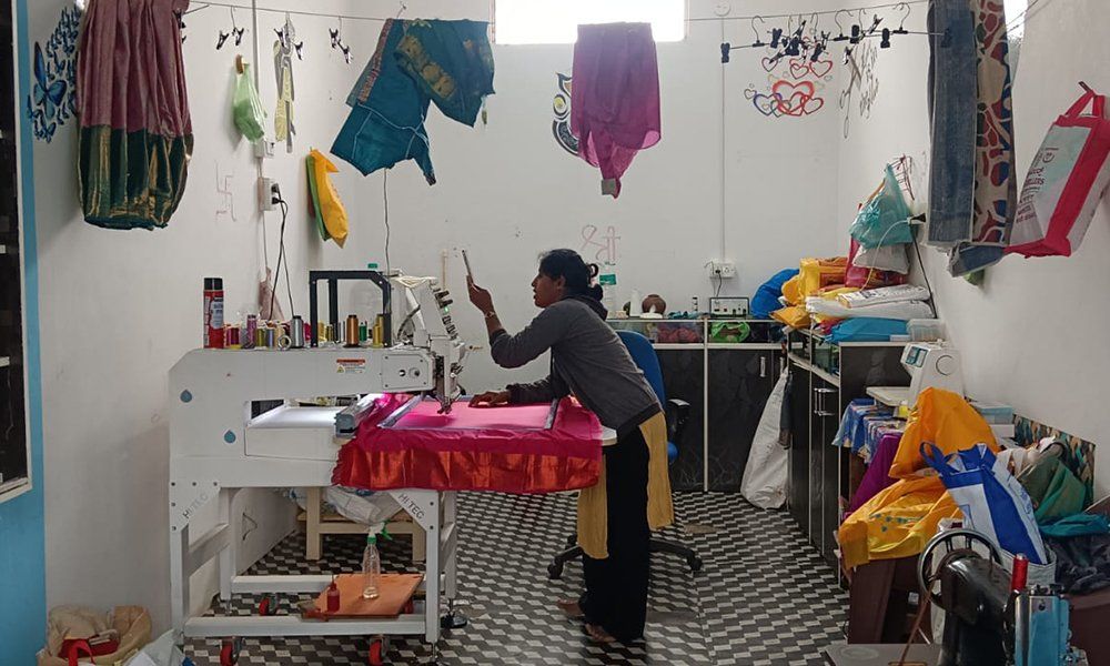 An Indian woman stitching in a fabric shop