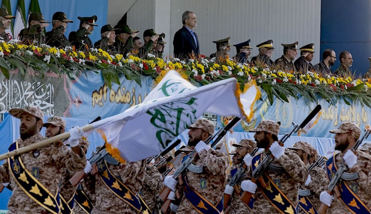 ​Iranian President Masoud Pezeshkian stands at attention while armed military personnel from the Islamic Revolutionary Guard Corps parade during a military parade commemorating the anniversary of the Iran-Iraq War in Tehran, on Sept. 21, 2024.