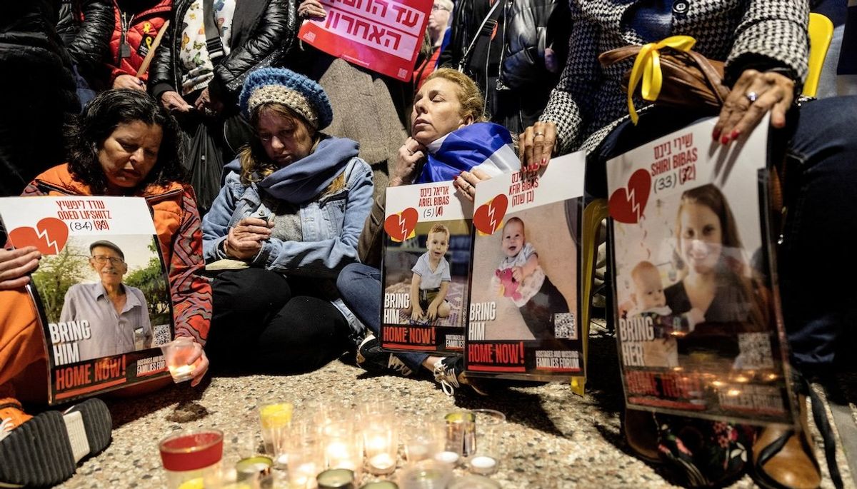 ​Israelis sit together as they light candles and hold posters with the images Oded Lifschitz, Shiri Bibas, and her two children, Kfir and Ariel Bibas, seized during the deadly Oct. 7, 2023 attack by Hamas, on the day the bodies of the deceased hostages were handed over under by Hamas on Feb. 20, 2025. 