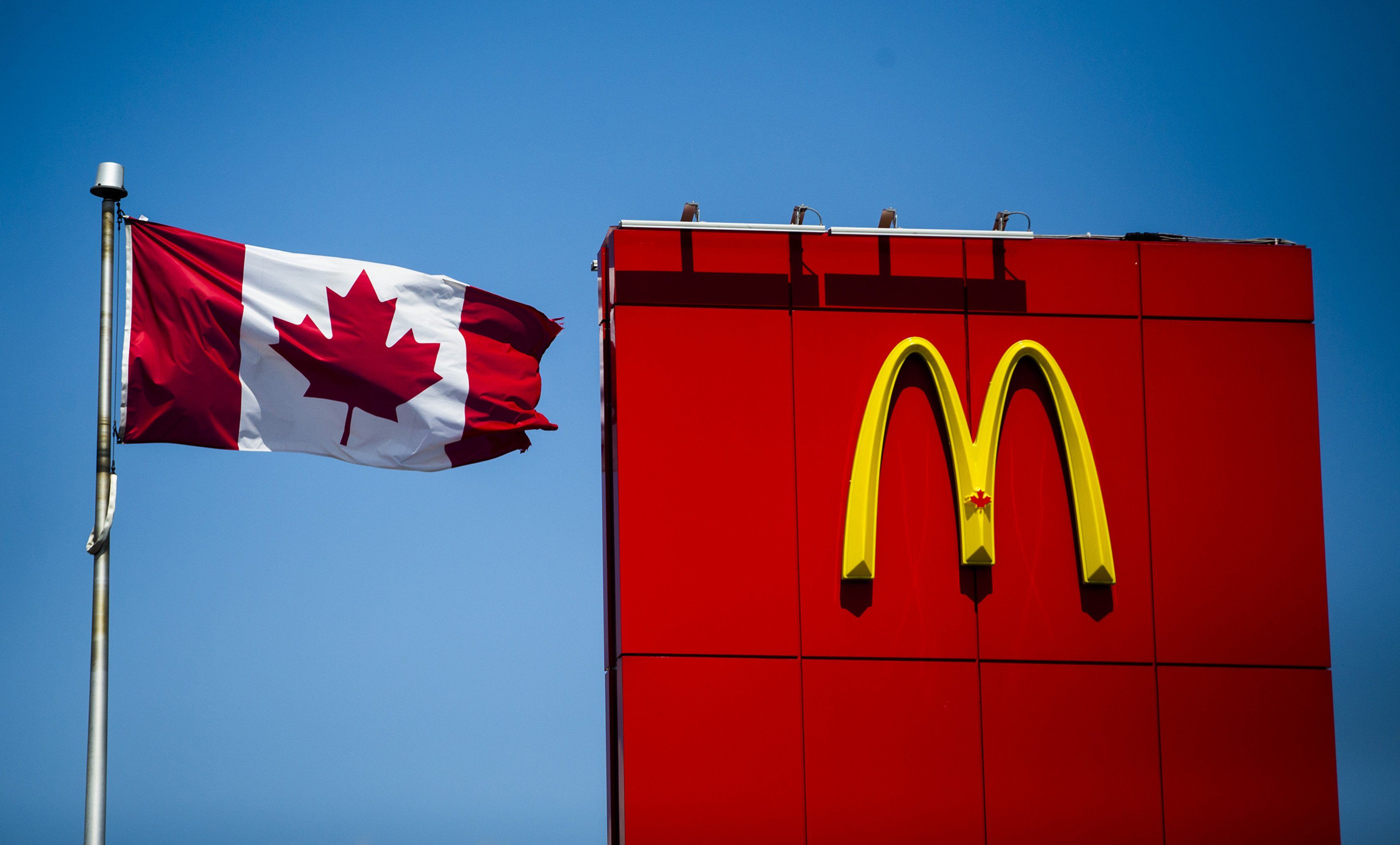 ​A Canadian flag waves beside McDonalds fast food restaurant in Toronto, May 1, 2014. Canada's foreign worker's program has expanded to lower-skilled jobs, especially at restaurant chains such as McDonald's Corp and Tim Hortons Inc.