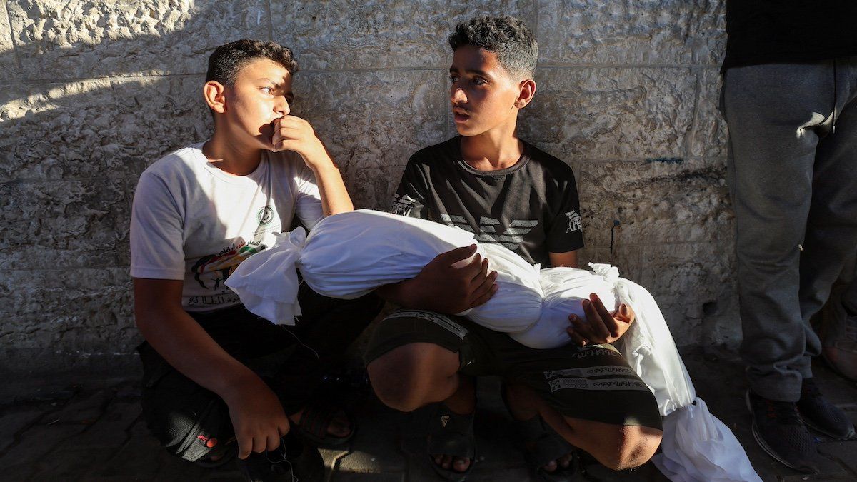 ​A cousin of a Palestinian child killed in an Israeli strike holds the body, amid the Israel-Hamas conflict, in Deir Al-Balah in the central Gaza Strip, August 20, 2024. 