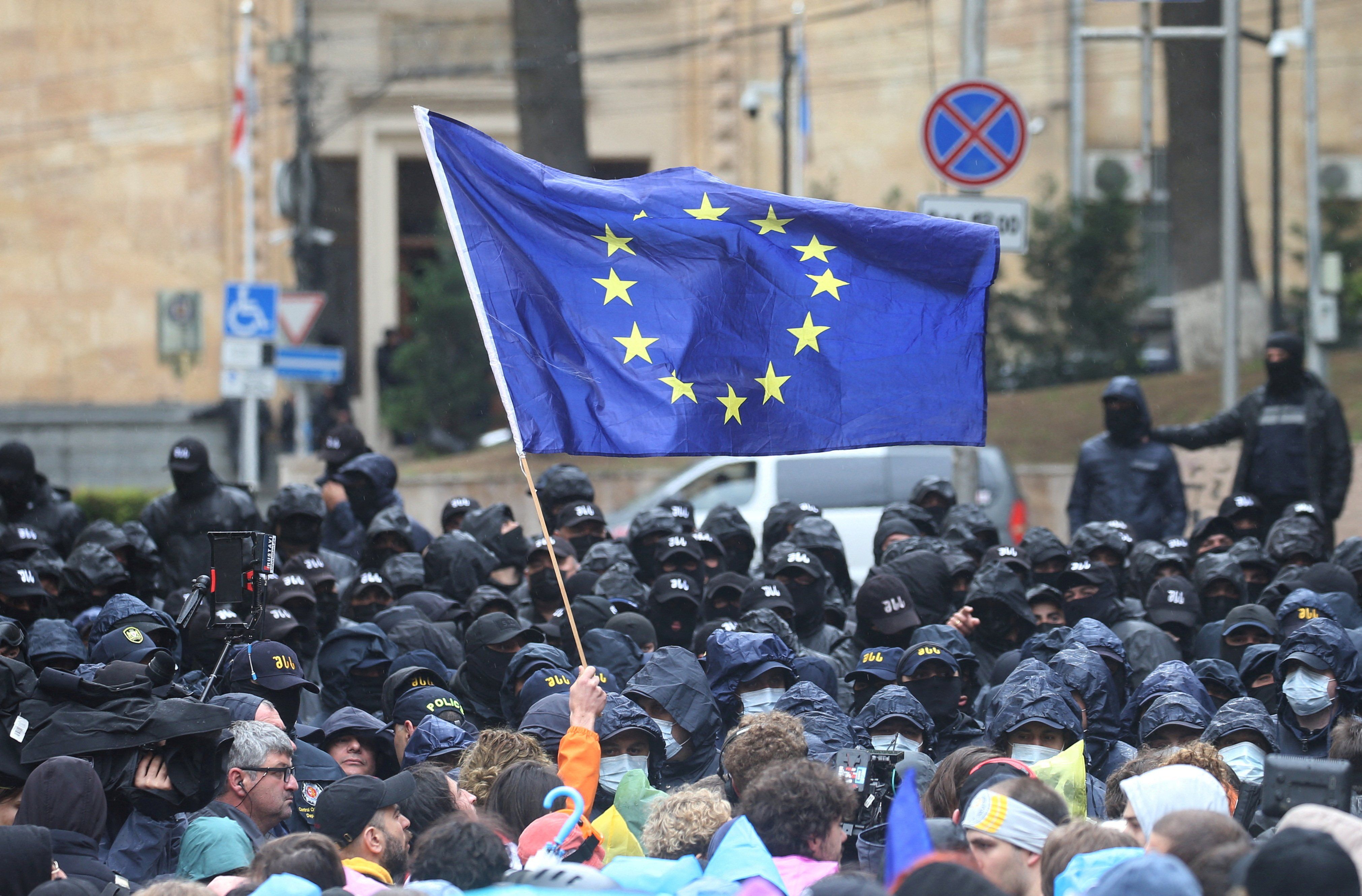 A demonstrator holds a European Union flag in front of law enforcement officers during a rally to protest against a bill on "foreign agents" in Tbilisi, Georgia, May 14, 2024. 