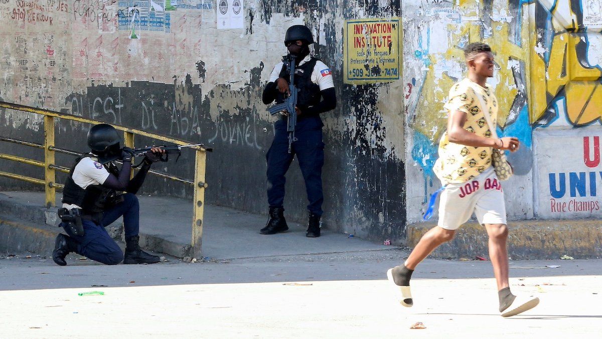 ​A man rushes past members of security forces during clashes between gangs and security forces, in Port-au-Prince, Haiti November 11, 2024. 