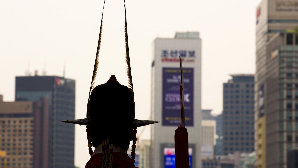 ​A palace guard is silhouetted against the skyline of Seoul as he stands outside Gyeongbokgung Palace in the centre of the South Korean capital, May 6, 2015. 