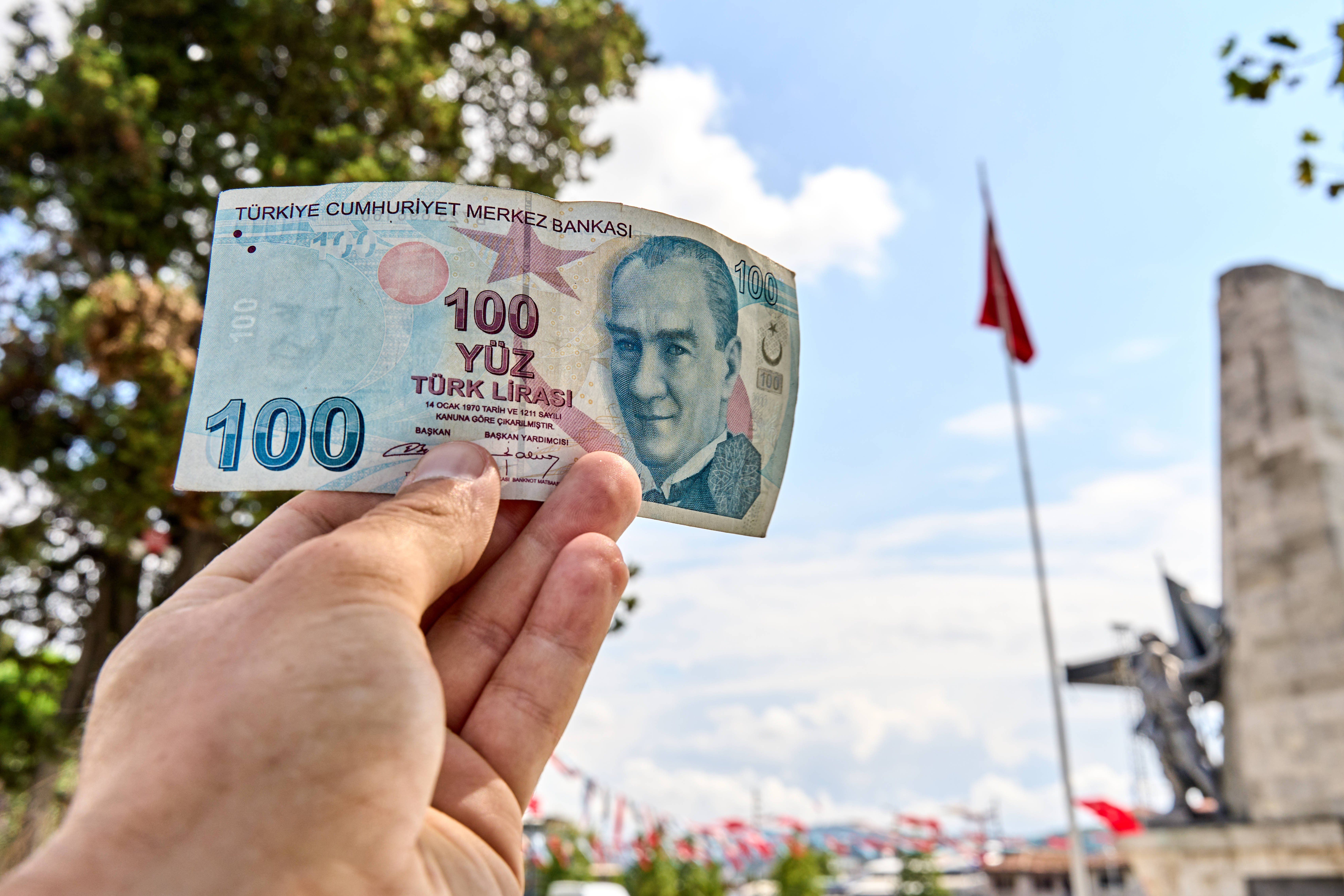 A person holds a 100 Turkish lira banknote while on vacation in Turkey. 