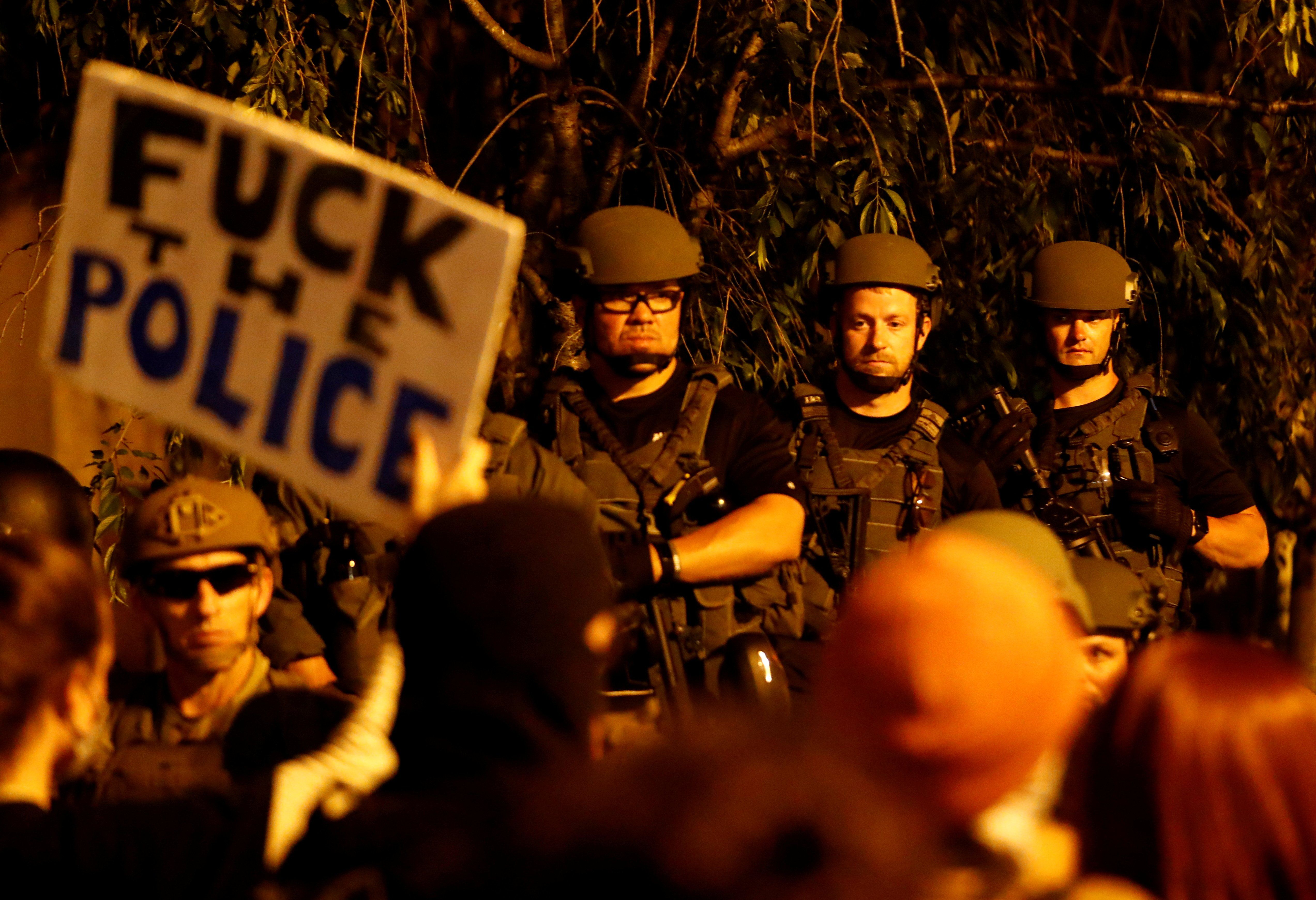 A protester holds up a sign as law enforcement personnel look on during a rally against the death in Minneapolis police custody of George Floyd, in Washington, DC.