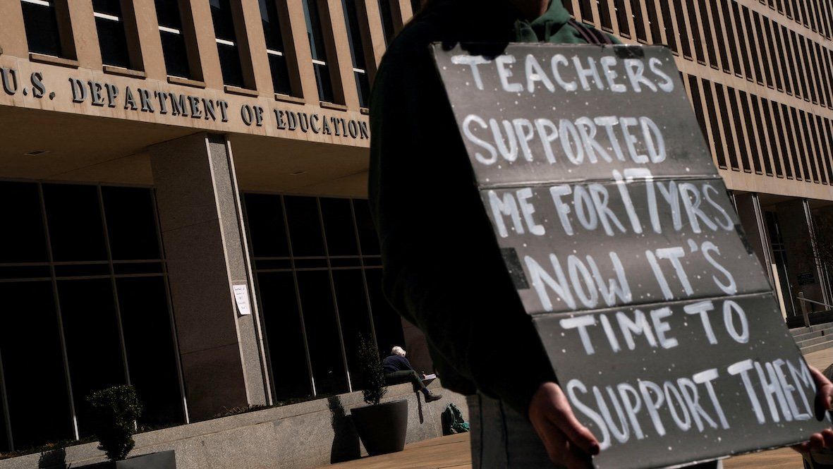 A protester stands near the US Department of Education headquarters after the agency said it would lay off nearly half its staff. 