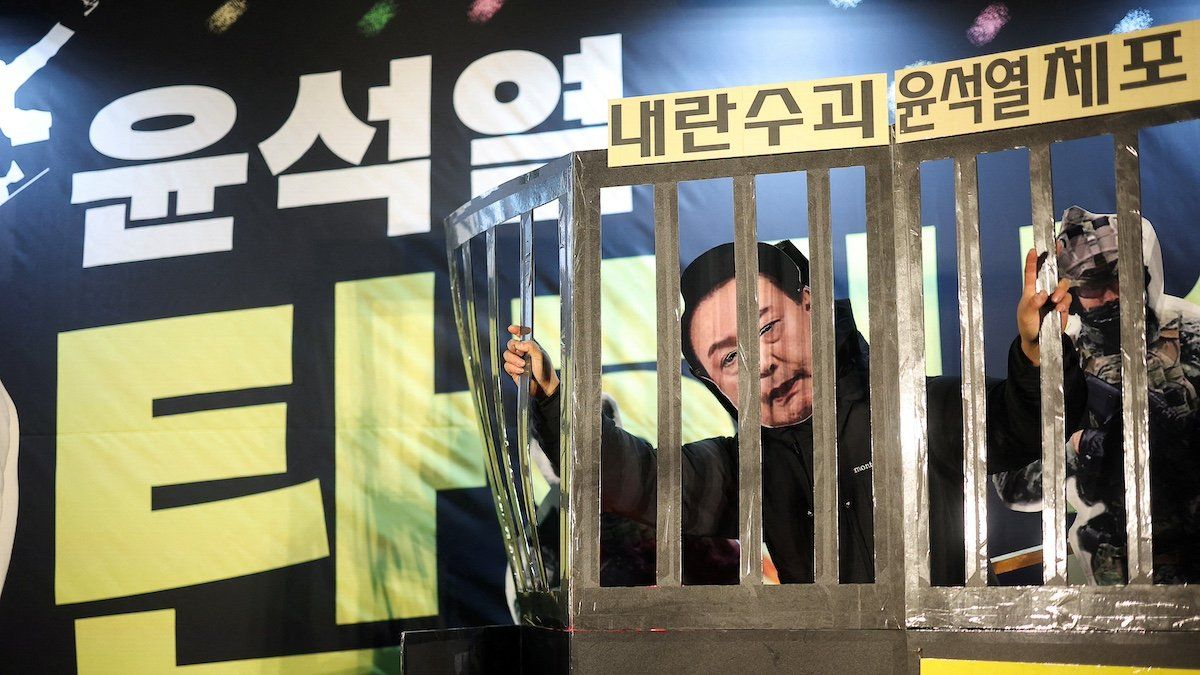 ​A protester wears a South Korean President Yoon Suk Yeol mask while holding a representation of prison bars, during a rally calling for the impeachment of the South Korean President, who declared martial law, which was reversed hours later, in front of the National Assembly in Seoul, South Korea, December 11, 2024. 