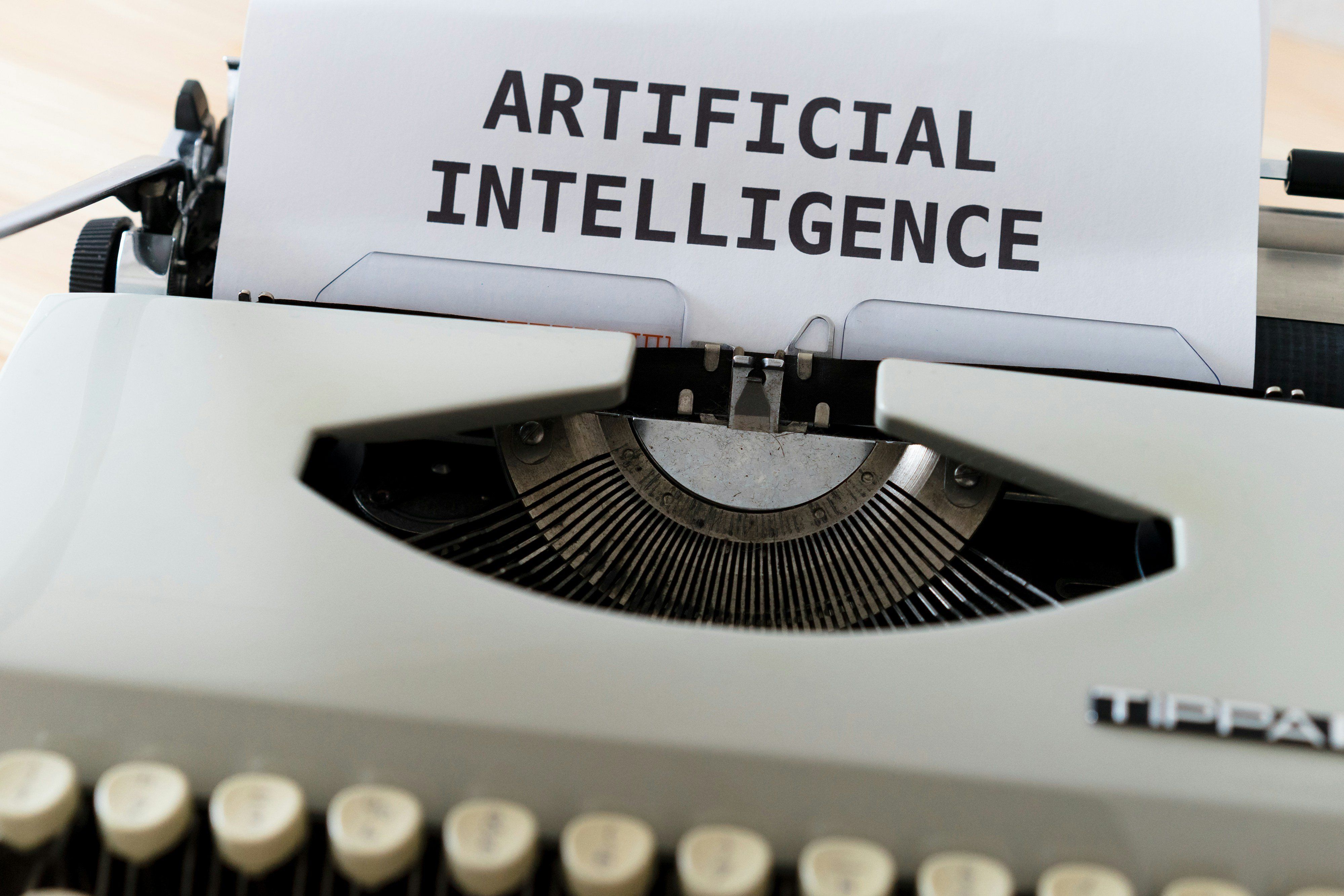 A typewriter and a white sheet of paper with the words "Artificial Intelligence" printed on it.