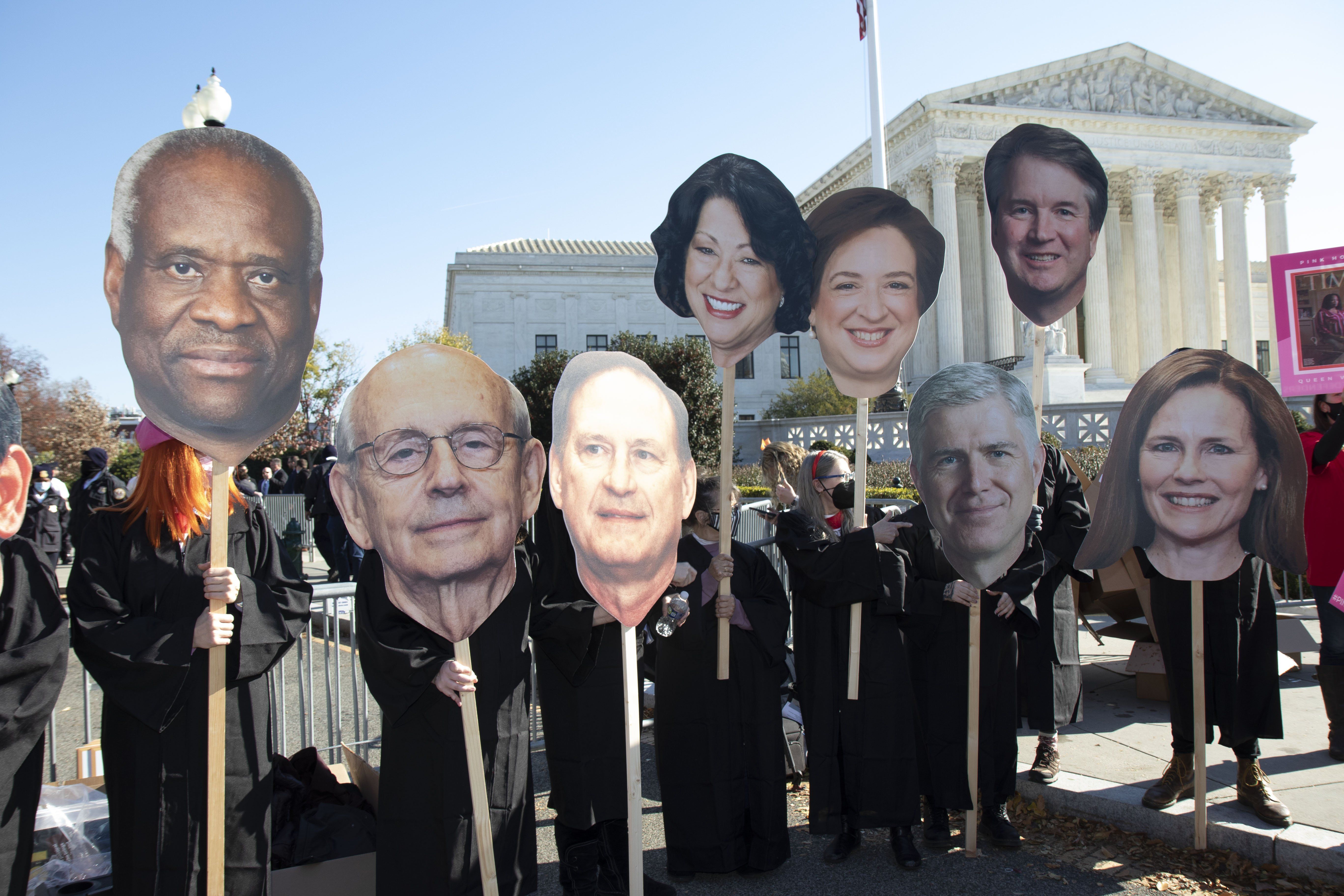 ​Activists carry caricatures of Supreme Court justices Rep. Marjorie Taylor-Greene peaks with people outside of the Supreme Court on Tuesday, December 1st, as the justices began hearing oral arguments in a case that challenges abortion rights in the United States. 