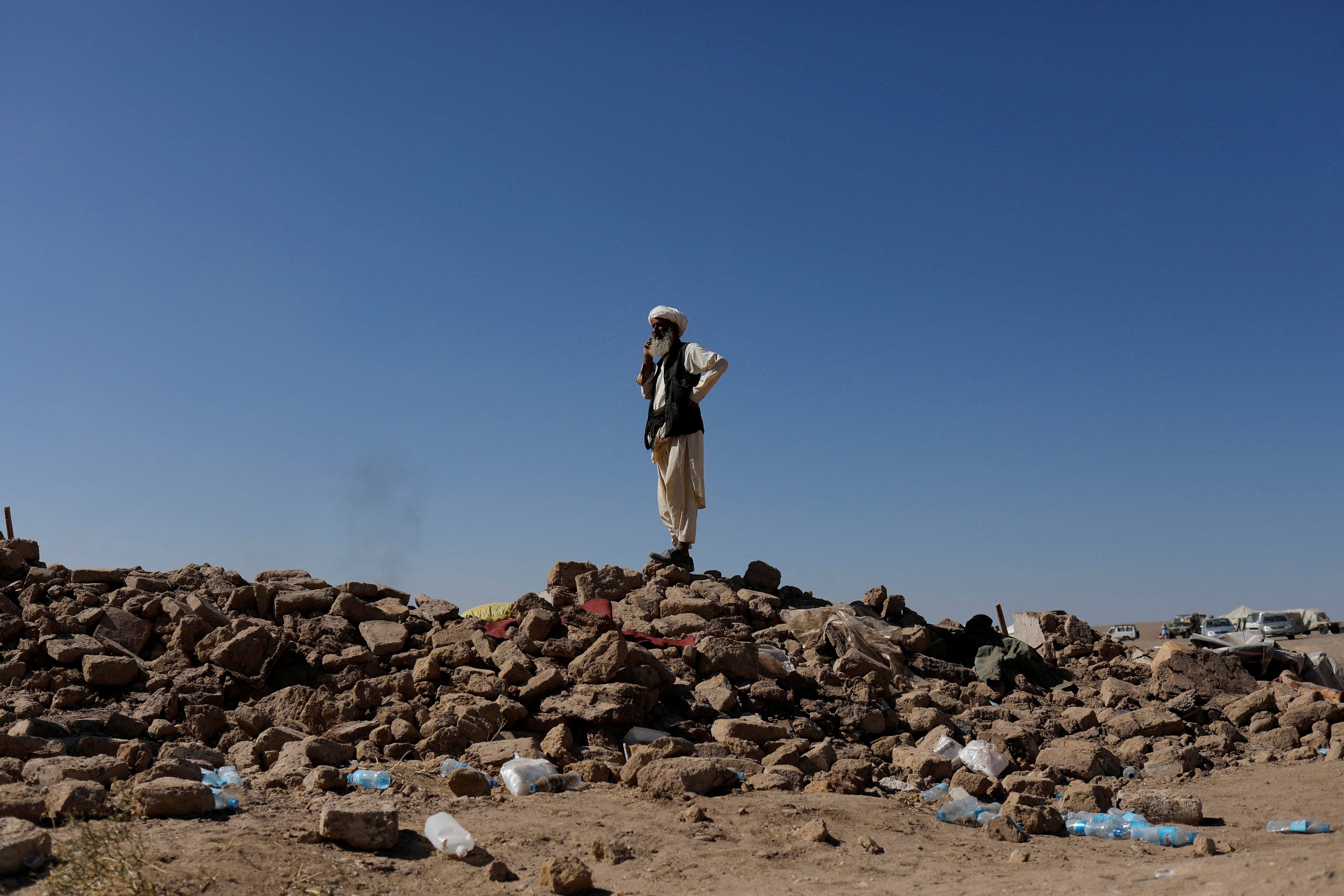 An Afghan man stands on the debris of damaged houses after the recent earthquake, in the district of Zinda Jan, in Herat, Afghanistan October 9, 2023.