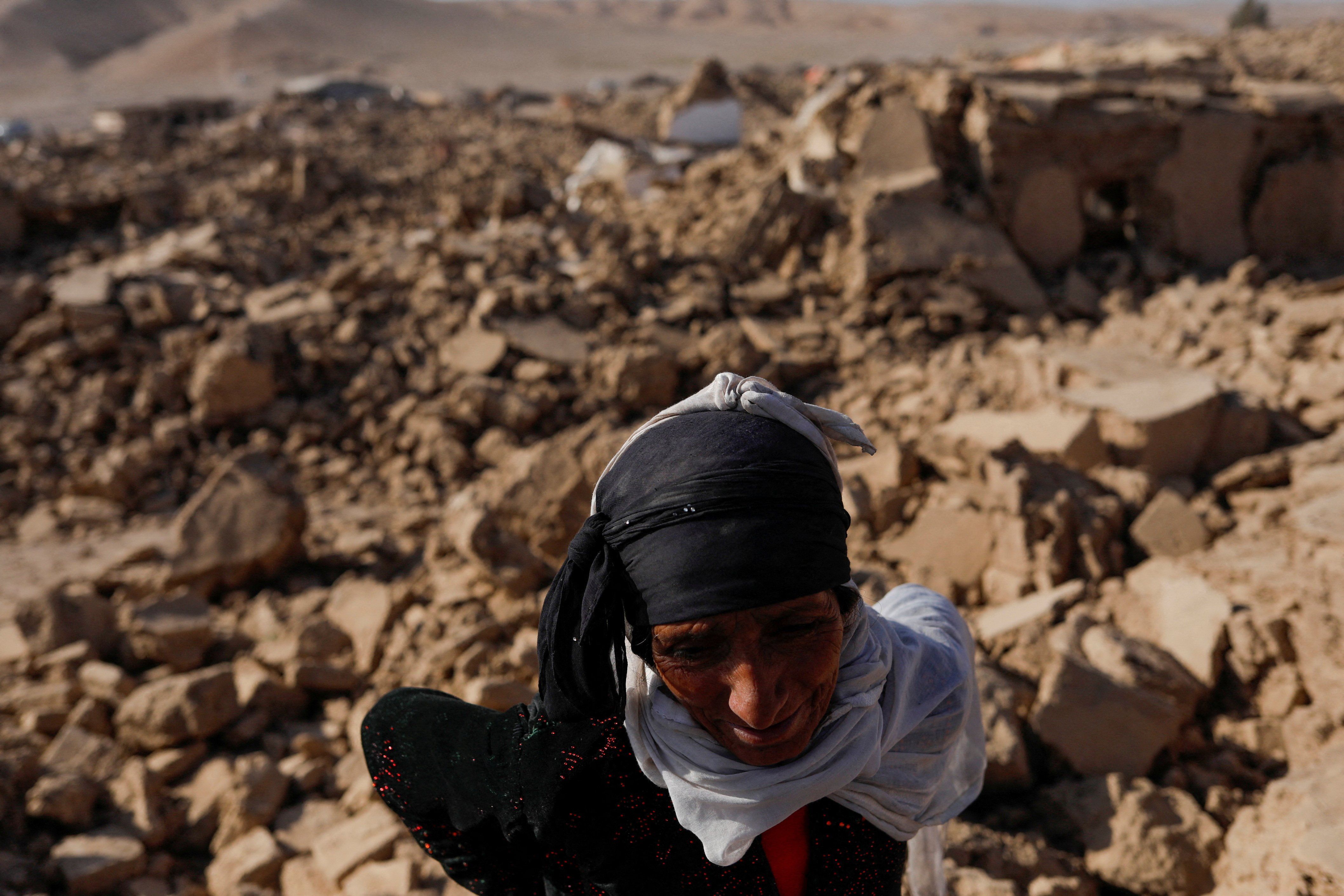 ​An Afghan woman stands next to her house after a recent earthquake in Chahak village in the Enjil district of Herat province, Afghanistan. Three deadly quakes have plagued the region this month.  