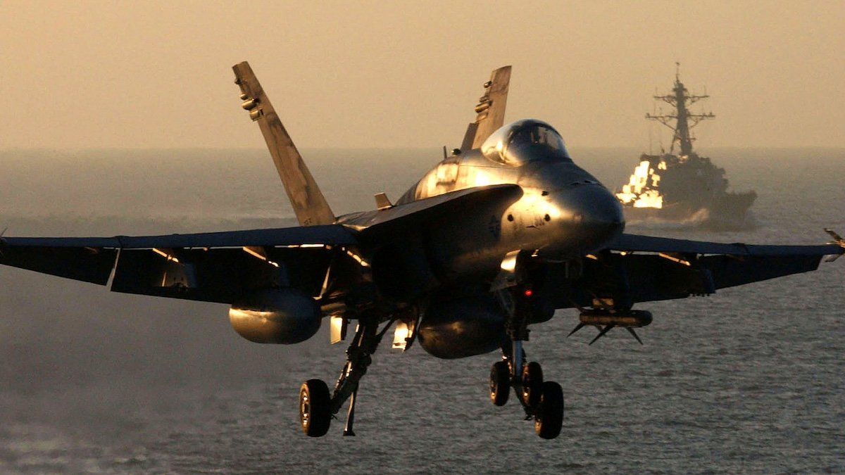 ​An F/A-18 Hornet approaches the flight deck of aircraft carrier USS Theodore Roosevelt as USS McFaul trails behind, October 30, 2001. Theodore Roosevelt and its carrier airwing are conducting missions in support of operation Enduring Freedom. 