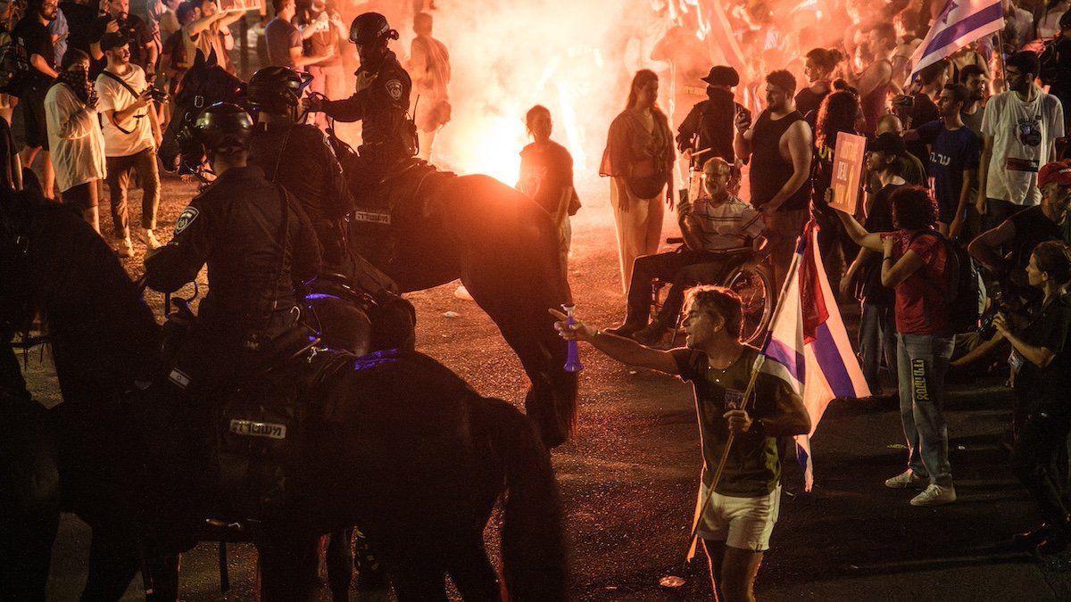 An Israeli protestor points at mounted police officers next to a bonfire on Democracy Square (Kaplan junction) during the demonstration. Over 100,000 of Israelis demonstrated with the hostages families against Prime Minister Benjamin Netanyahu, demanding an immediate hostage deal and ceasefire as they set up bonfires on Kaplan Junction.