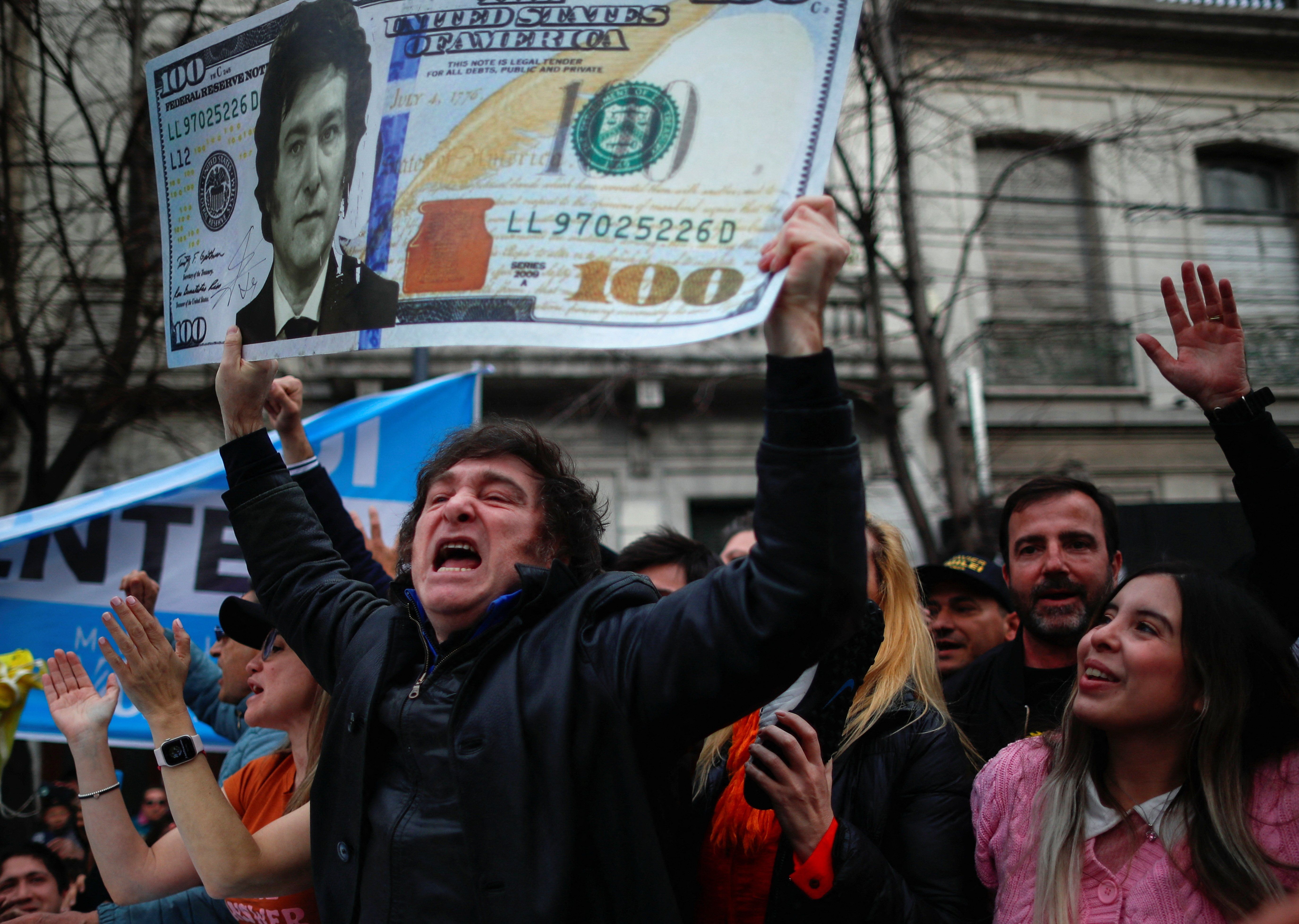 ​Argentine presidential candidate Javier Milei of La Libertad Avanza coalition holds a placard depicting a dollar bill with his face on it, during a campaign rally in La Plata, Buenos Aires, Argentina, September 12, 2023. 