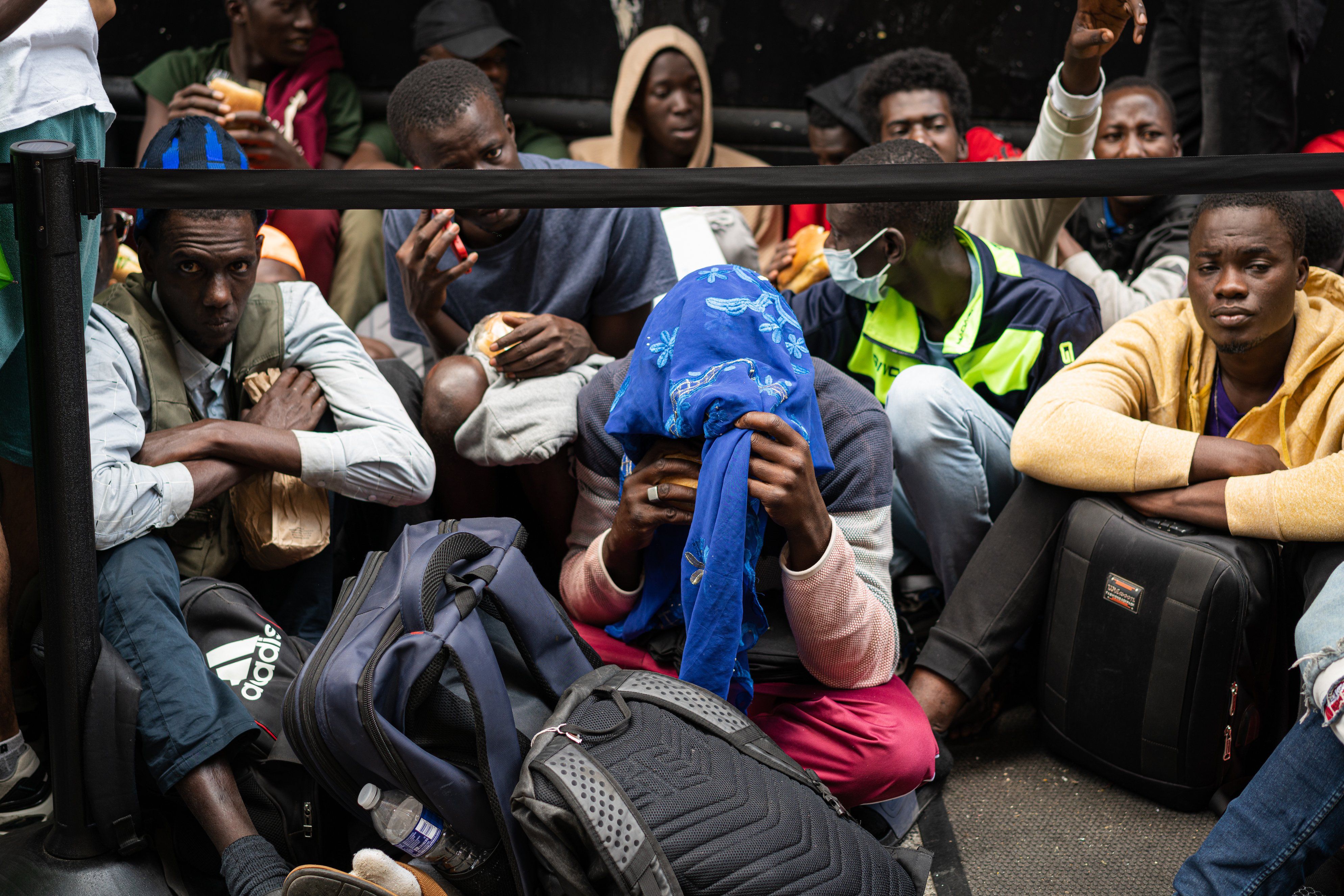 Asylum seekers fill the sidewalk outside of the Roosevelt hotel in midtown Manhattan, New York City.