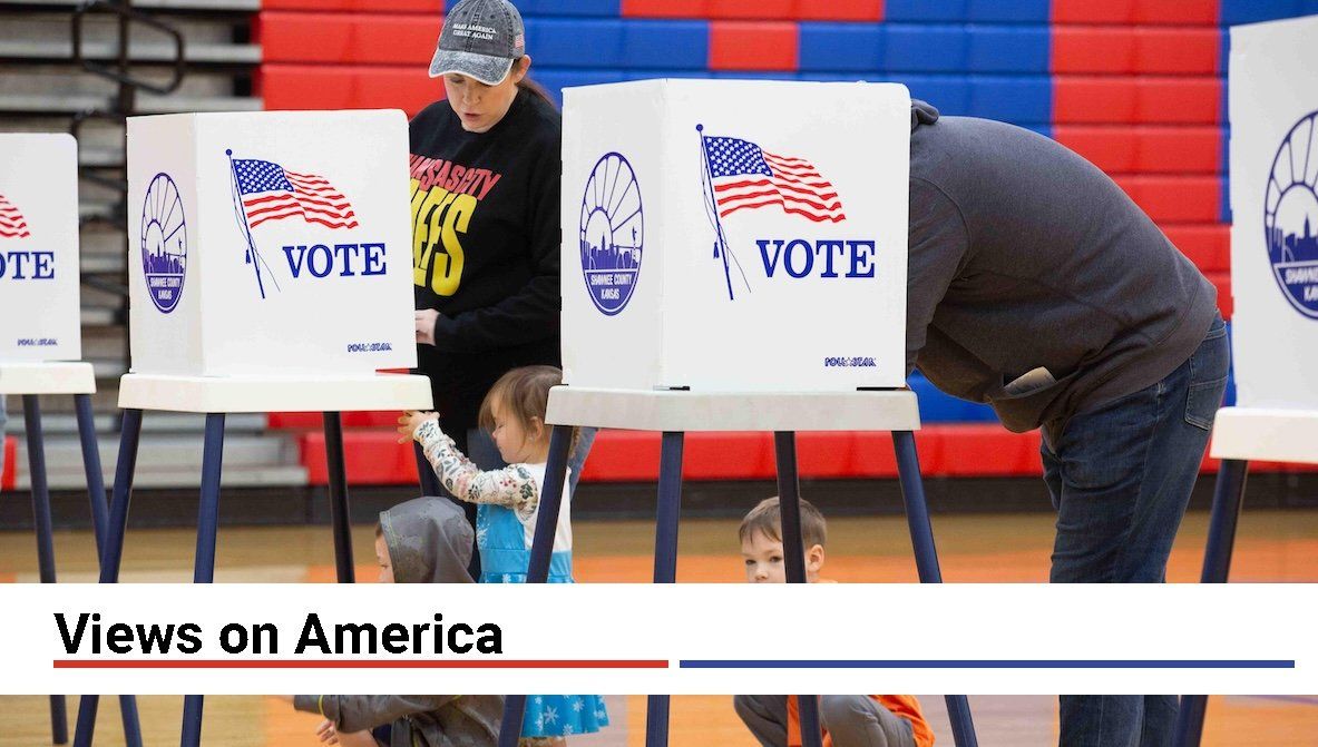 ​Aubrey and Taylor Endicott cast their votes while their children, from left, Sterling, 5, Adelaide, 3, and Lincoln, 7, wait patiently under the voting tables at Shawnee Heights Middle School on Tuesday, Nov. 5, 2024.