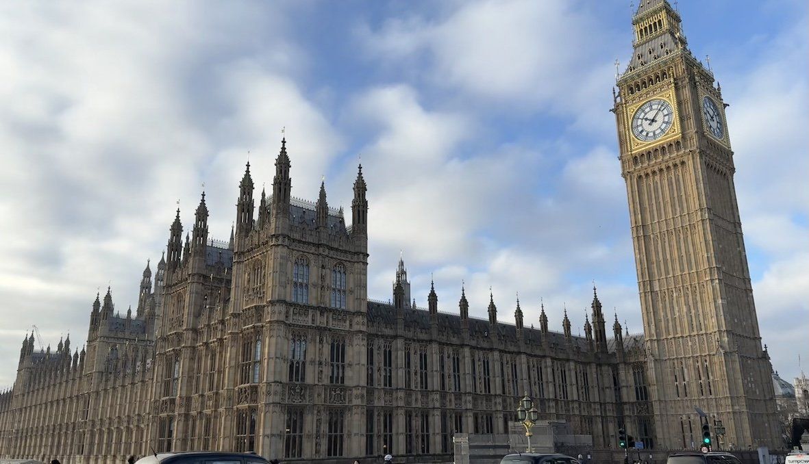 Cabs drive along Westminster Bridge in front of the British Parliament with the Elizabeth Tower and the famous Big Ben bell.