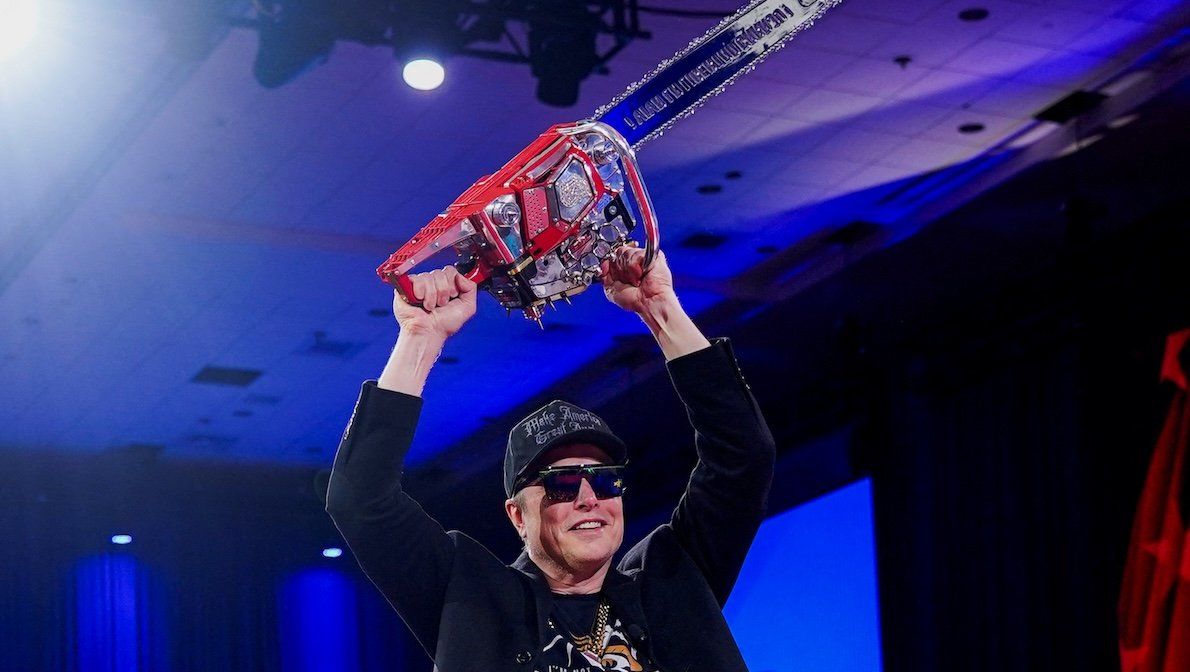 ​Elon Musk holds a chainsaw onstage as he attends the Conservative Political Action Conference in National Harbor, Maryland, on Feb. 20, 2025. The idea is that he's taking a chainsaw to the federal bureaucracy. 