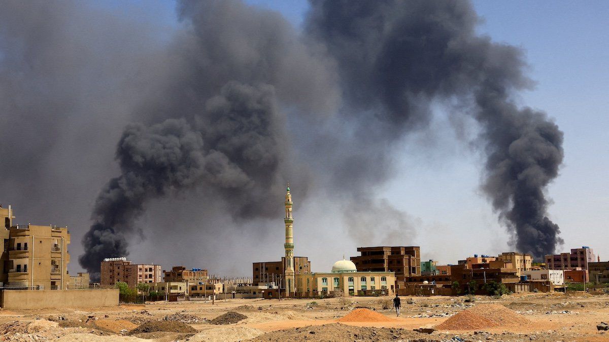 ​FILE PHOTO: A man walks while smoke rises above buildings after aerial bombardment, during clashes between the paramilitary Rapid Support Forces and the army in Khartoum North, Sudan, May 1, 2023. 