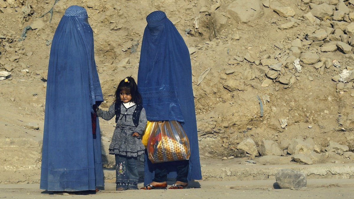 ​FILE PHOTO: Afghan women clad in burkas wait for transportation on a road in Kabul November 5, 2012. 