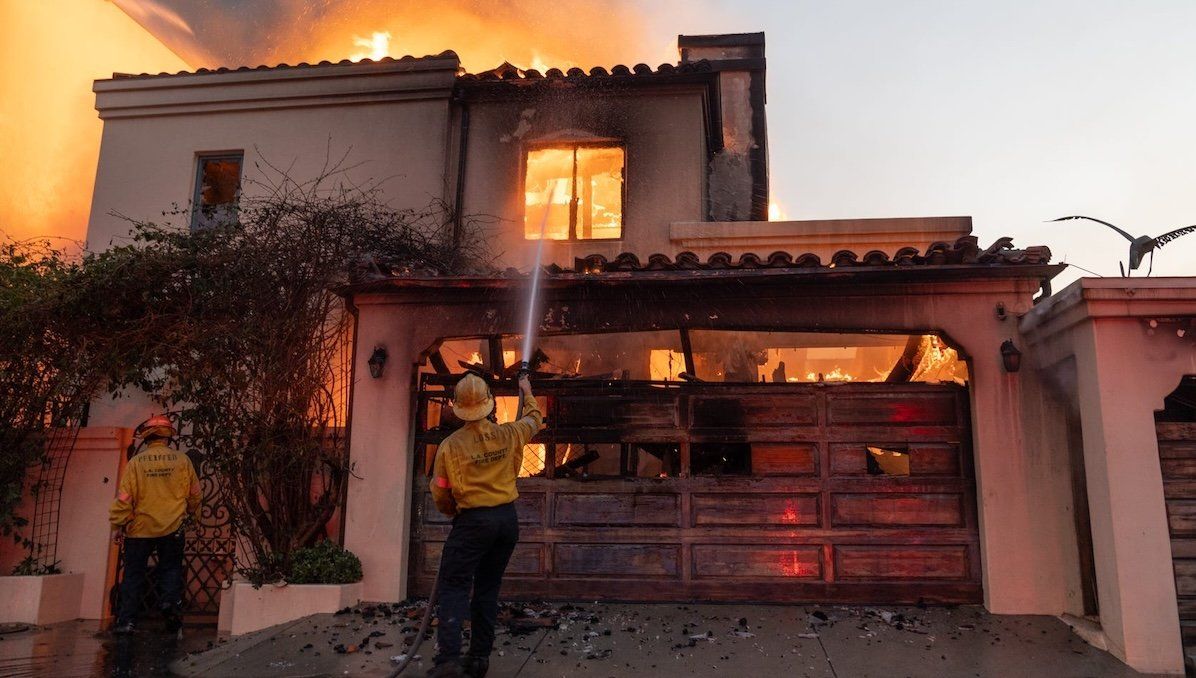 ​Firefighters attempt to extinguish a fire in a home along the Pacific Coast Highway in the Pacific Palisades neighborhood.