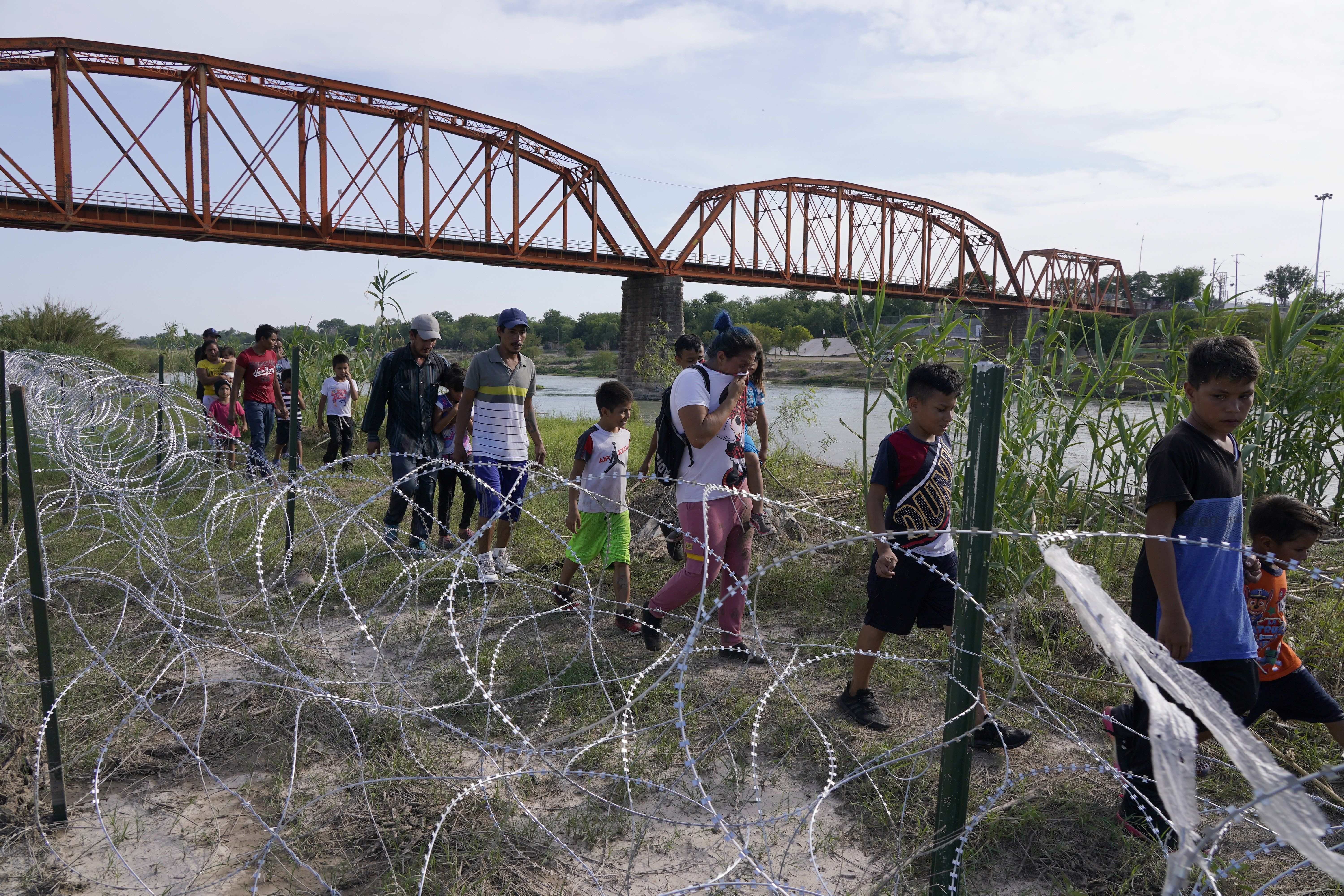 Migrants, most with children follow a path along the concertina wire where ultimatley they will placed under guard by Border Patrol after having crossed the Rio Grande on May 27 2022 in Eagle Pass Texas, USA. Title 42, the Trump era mandate which was set to prevent migrants from entering the US, was to expire on May 23 but was blocked by a lawsuit filed by several states citing that the move to strike down the law “failed to meet standards set by the Administrative Procedure Act” and that there is no permanent solution to handling the inevitable surge in immigration. Opponents to upholding of the law voiced their demands stating that Title 42 is illegal in that it violates immigration laws that prevents immigrants from their right to seek asylum. Since the implementation of Title 42 in March 2020, US Customs and Border Protection has effected “more than 1.8 million expulsions, mostly on the southern border of the US-Mexico Border”. 