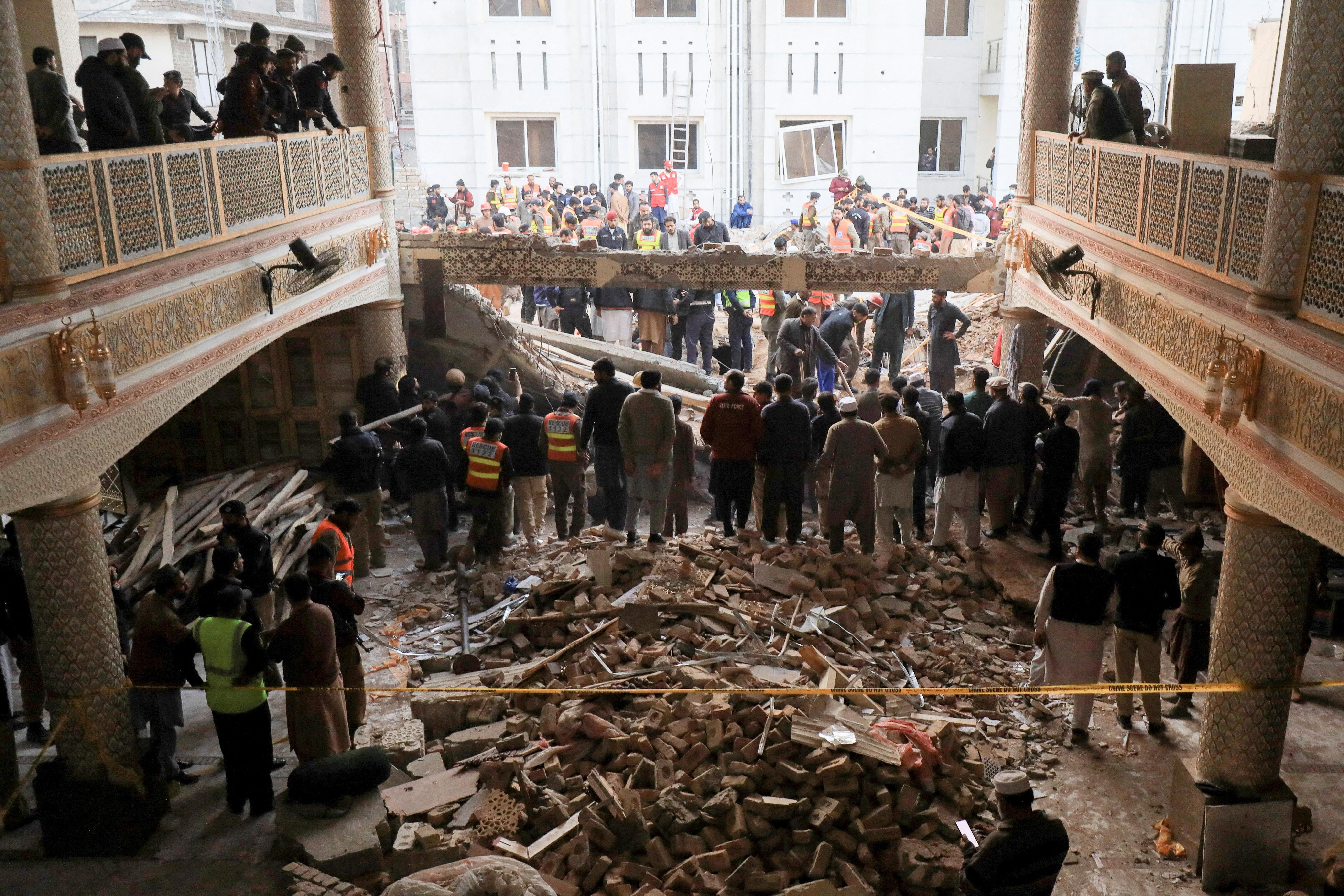 People and rescue workers gather to look for survivors after a suicide blast in a mosque in Peshawar, Pakistan 