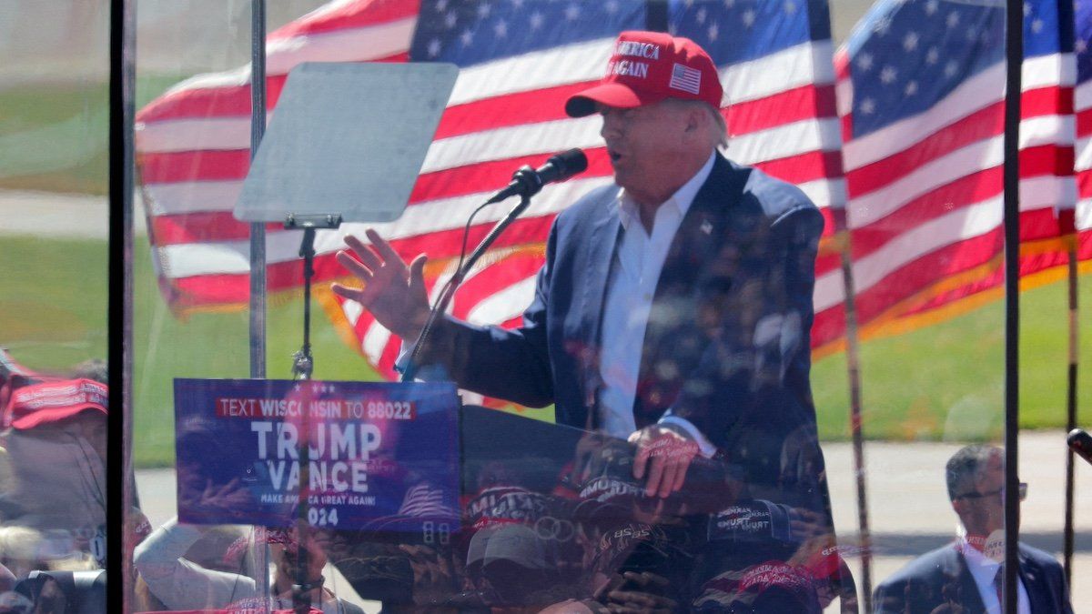 People are reflected in protective glass as they listen to Republican presidential nominee and former U.S. President Donald Trump as he speaks during a rally in Mosinee, Wisconsin, U.S. September 7, 2024. 