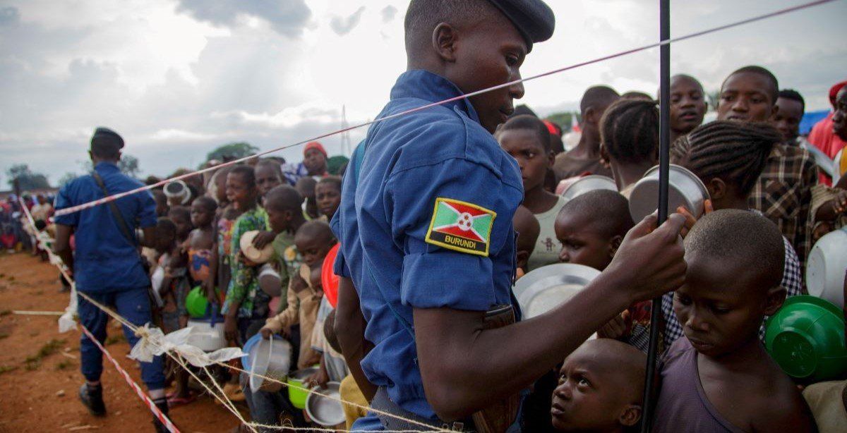 ​Police officers stand guard as Congolese youngsters jostle to receive relief food, after fleeing from renewed clashes between M23 rebels and the Armed Forces of the Democratic Republic of the Congo. February 18, 2025. 