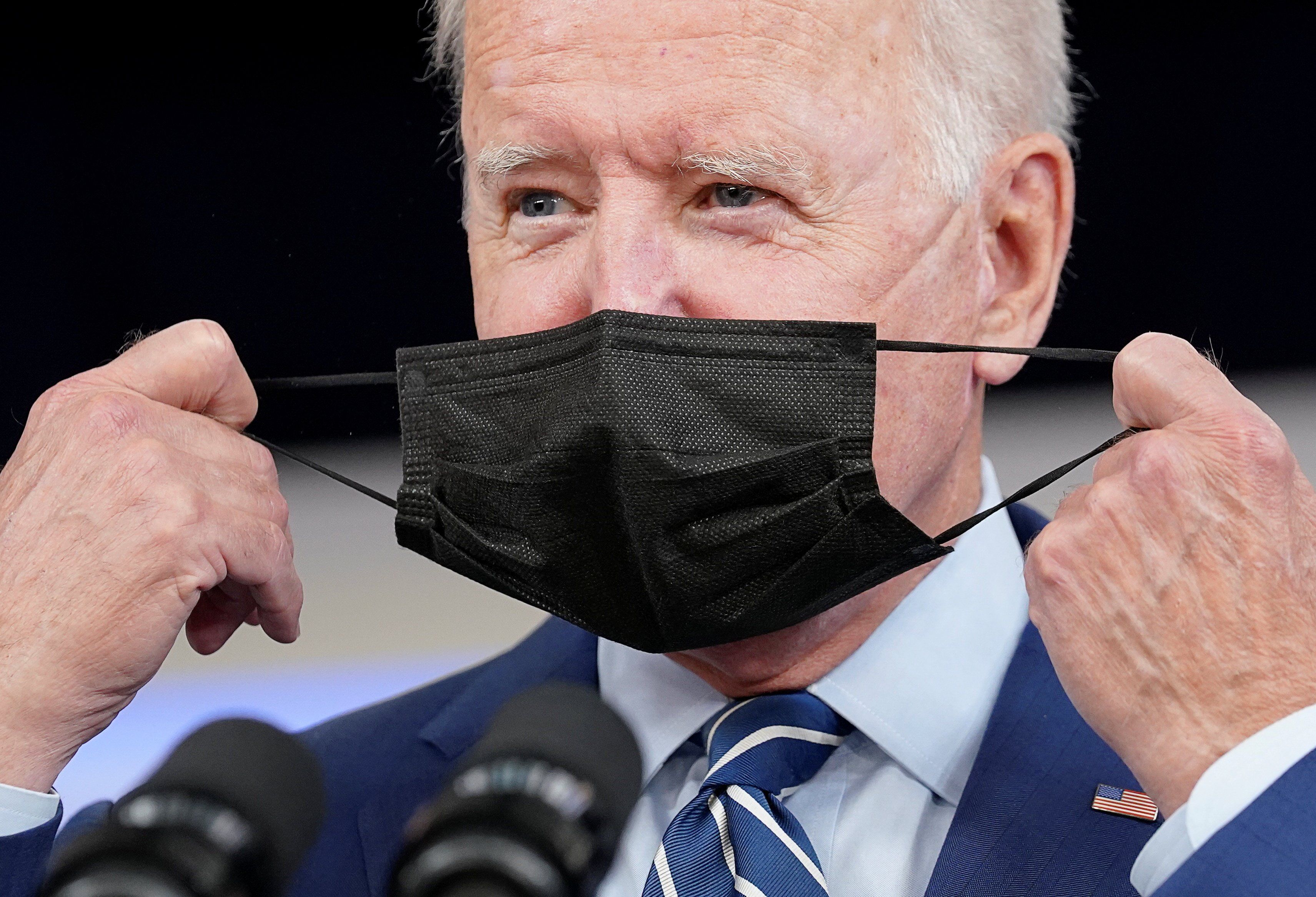 U.S. President Joe Biden removes his face mask prior to receiving his coronavirus disease (COVID-19) booster vaccination in the Eisenhower Executive Office Building's South Court Auditorium at the White House in Washington, U.S., September 27, 2021. 