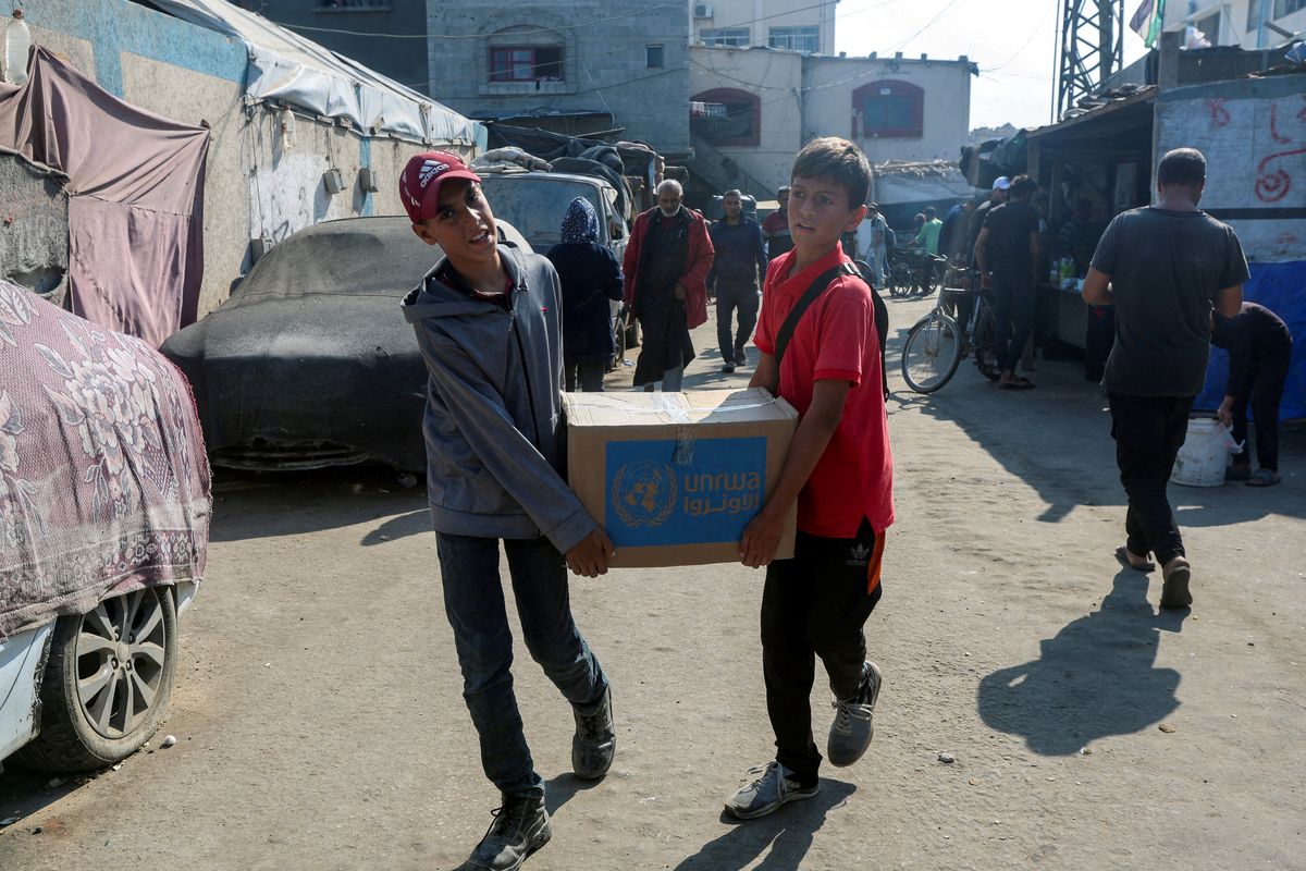 ​Palestinians carry an aid box distributed by the United Nations Relief and Works Agency (UNRWA), amid the Israel-Hamas conflict, in Deir Al-Balah, central Gaza Strip, November 4, 2024. 