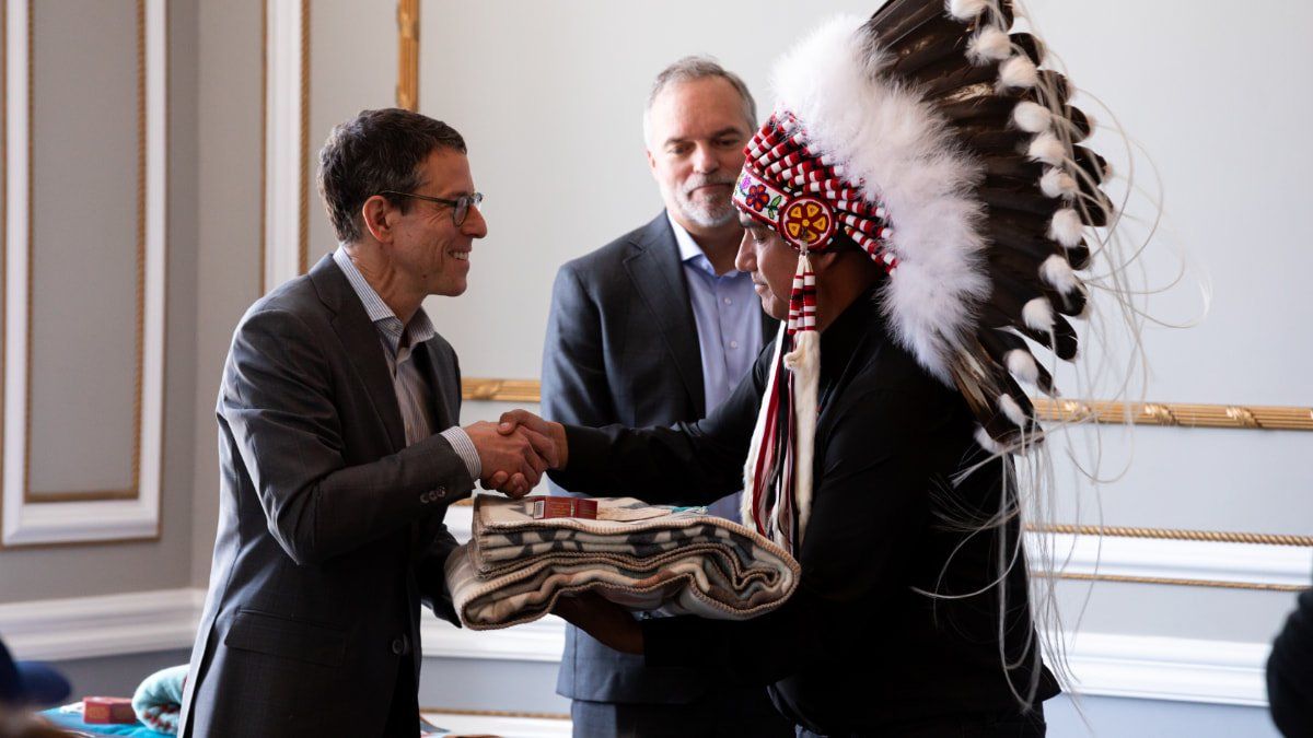 Person shaking hands and receiving a present from another Indigenous person